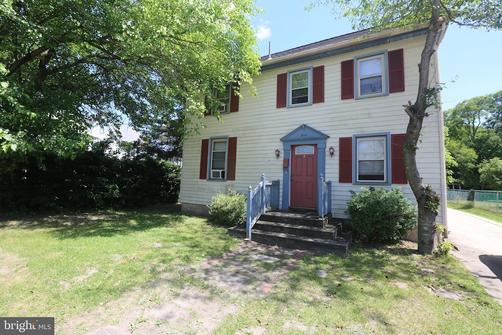 colonial inspired home featuring cooling unit and a front lawn