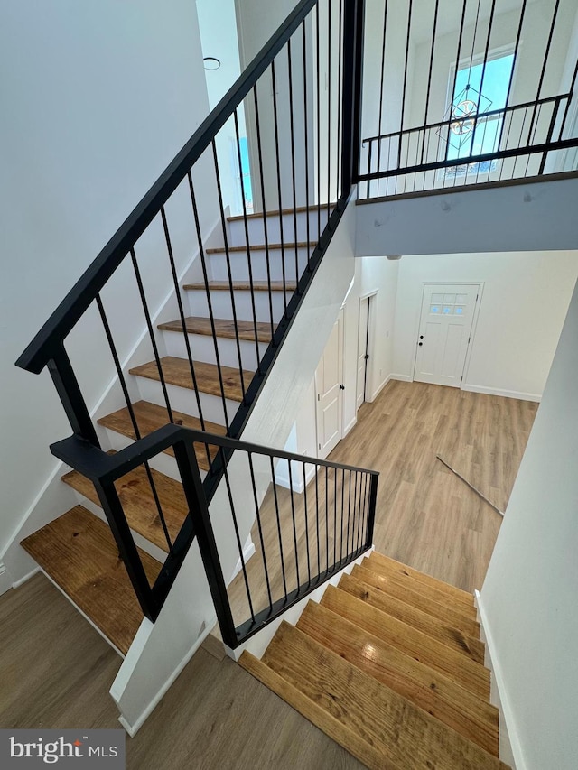 stairway featuring a towering ceiling and hardwood / wood-style floors