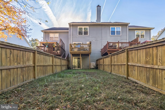 rear view of house with a wooden deck and a lawn