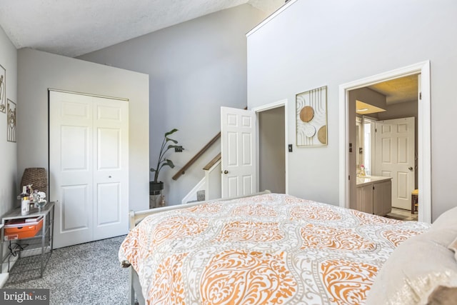 carpeted bedroom with a closet, ensuite bathroom, and a textured ceiling