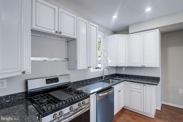 kitchen featuring white cabinets, dark stone countertops, dark hardwood / wood-style floors, sink, and stainless steel appliances