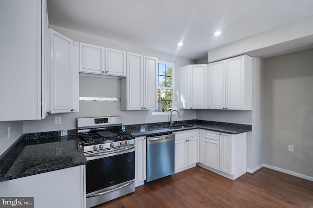 kitchen featuring dark hardwood / wood-style floors, stainless steel appliances, dark stone counters, sink, and white cabinetry