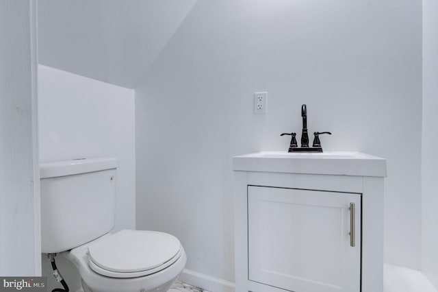 bathroom with toilet, lofted ceiling, and vanity