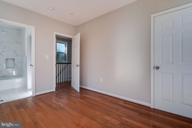 unfurnished bedroom with hardwood / wood-style floors and ensuite bath