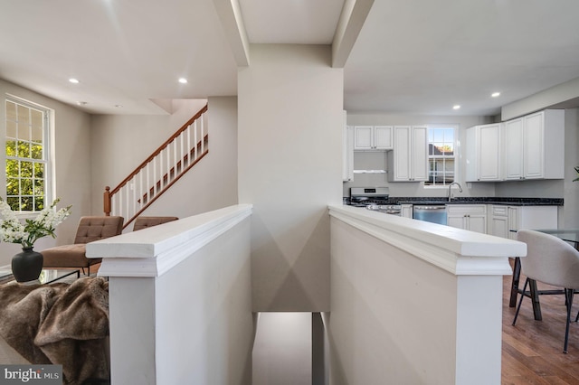 kitchen with white cabinetry, kitchen peninsula, stainless steel appliances, and a healthy amount of sunlight