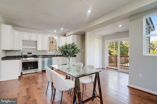 kitchen with sink, appliances with stainless steel finishes, hardwood / wood-style flooring, and white cabinets