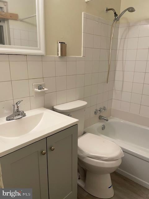 full bathroom with backsplash, toilet, vanity, hardwood / wood-style flooring, and tiled shower / bath combo