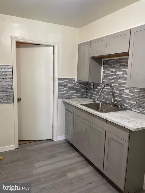 kitchen with gray cabinets, sink, and light hardwood / wood-style flooring