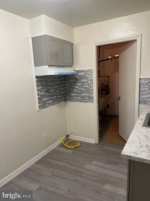 kitchen with ventilation hood, light hardwood / wood-style floors, gray cabinetry, and backsplash