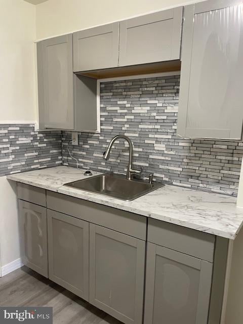 kitchen featuring sink, gray cabinetry, and backsplash