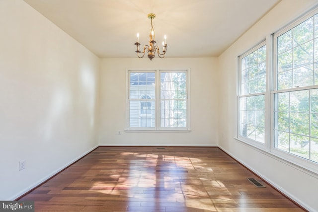 unfurnished dining area with dark wood-type flooring, an inviting chandelier, and plenty of natural light