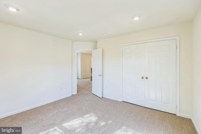 unfurnished bedroom featuring light colored carpet and a closet