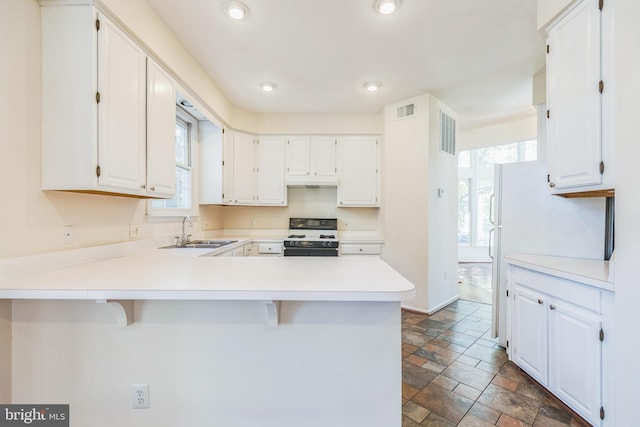 kitchen with a breakfast bar area, kitchen peninsula, sink, black / electric stove, and white cabinets