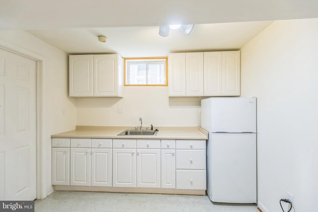 kitchen featuring white cabinetry, white fridge, and sink