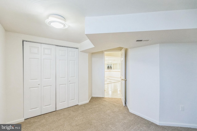 unfurnished bedroom featuring light carpet and a closet