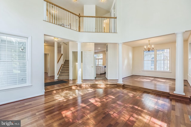 unfurnished living room with a high ceiling, hardwood / wood-style flooring, and an inviting chandelier