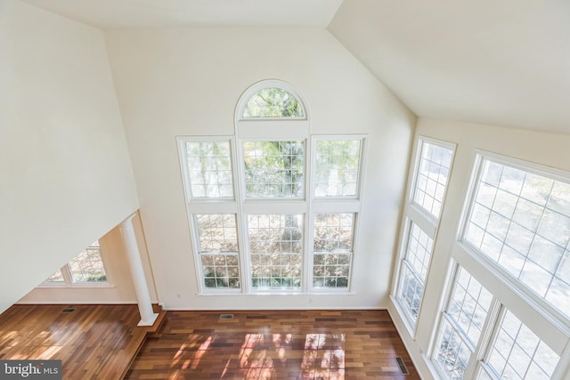 unfurnished living room featuring dark wood-type flooring, high vaulted ceiling, and a healthy amount of sunlight