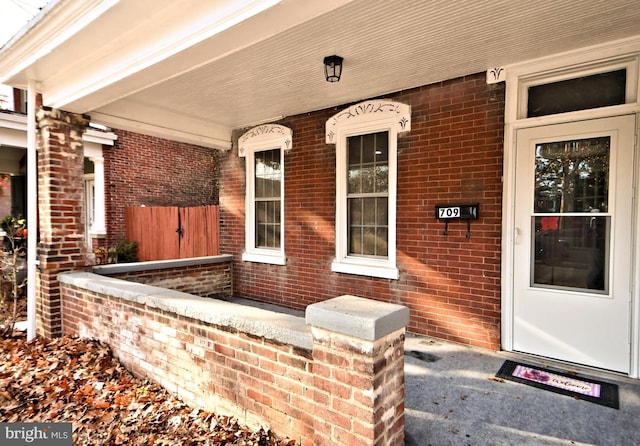 entrance to property featuring brick siding and covered porch