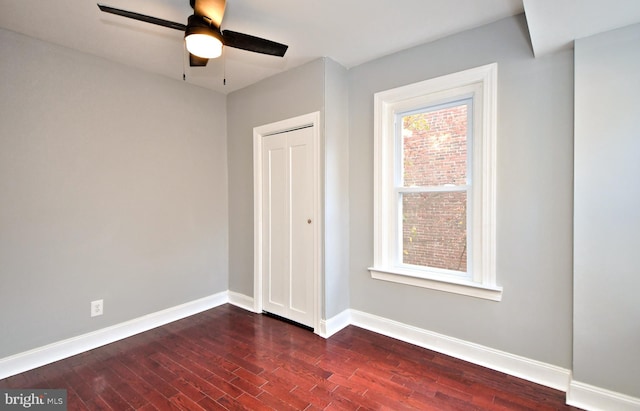 unfurnished bedroom featuring dark wood finished floors, baseboards, a closet, and a ceiling fan