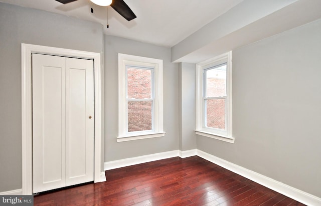 unfurnished bedroom featuring dark wood-style floors, multiple windows, and baseboards