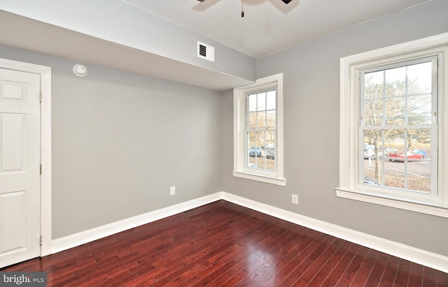 spare room featuring dark wood-style flooring, a ceiling fan, baseboards, and a smoke detector
