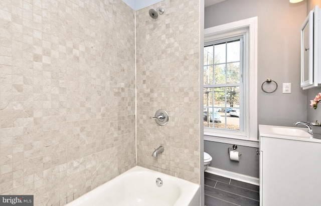 bathroom with toilet, vanity, bathtub / shower combination, and baseboards
