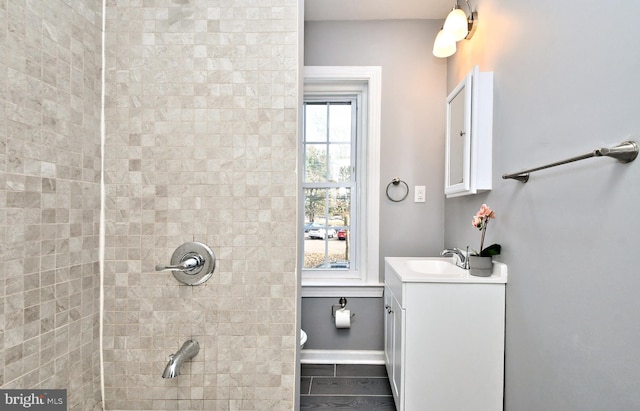 bathroom featuring vanity, a shower, and baseboards