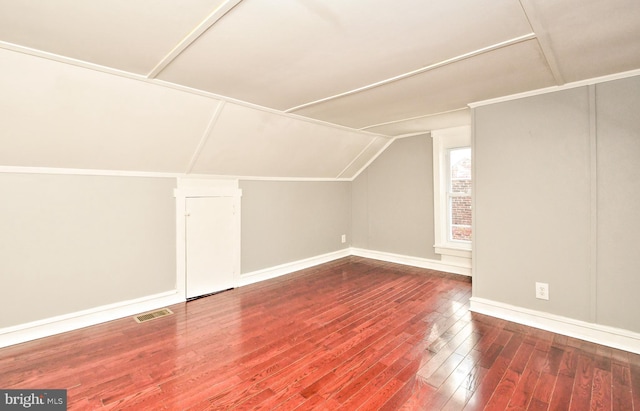 additional living space featuring vaulted ceiling, wood-type flooring, and baseboards
