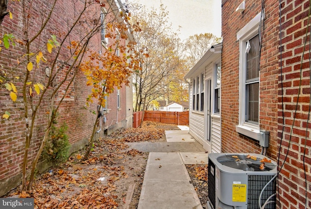 view of home's exterior featuring brick siding, central air condition unit, and fence