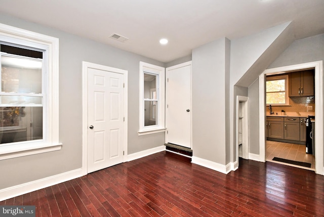 unfurnished living room featuring dark wood-style floors, baseboards, recessed lighting, and a sink