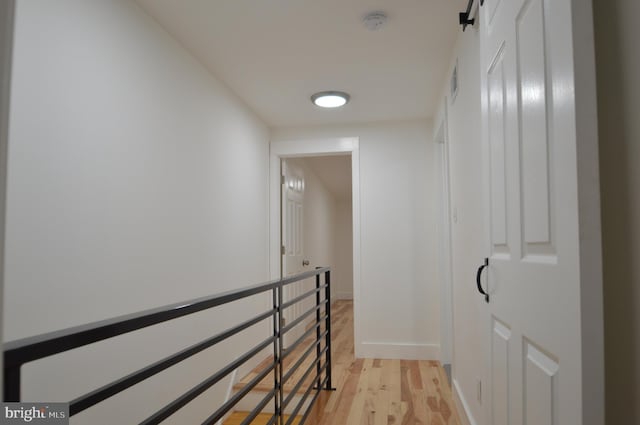 hall with baseboards, visible vents, and light wood finished floors