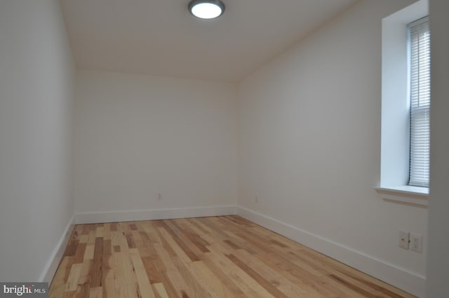 spare room featuring baseboards and light wood-style floors