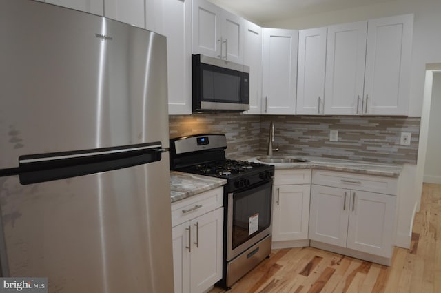 kitchen featuring appliances with stainless steel finishes, light hardwood / wood-style floors, and white cabinets