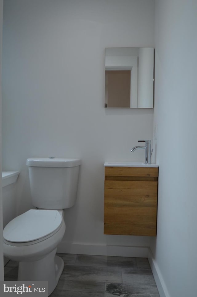 half bathroom featuring toilet, vanity, and baseboards
