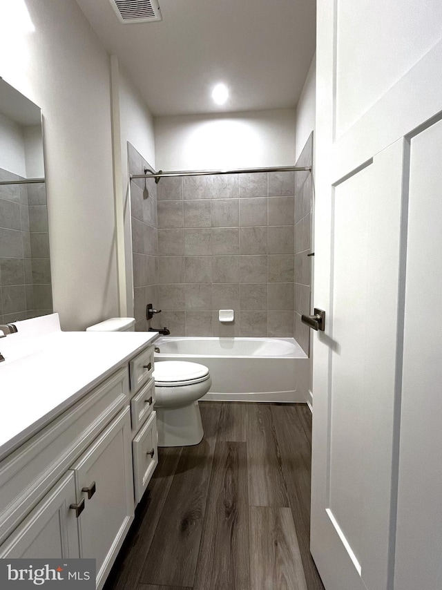 full bathroom featuring hardwood / wood-style floors, vanity, tiled shower / bath combo, and toilet