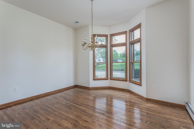 empty room featuring hardwood / wood-style flooring, a baseboard radiator, and a chandelier