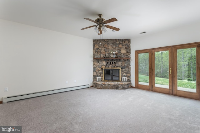 unfurnished living room with baseboard heating, a stone fireplace, carpet flooring, and ceiling fan