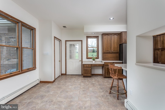 kitchen with built in desk, a baseboard radiator, and light tile patterned floors