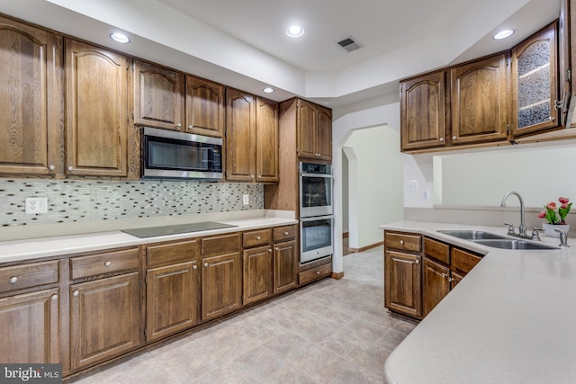 kitchen with appliances with stainless steel finishes, sink, and decorative backsplash