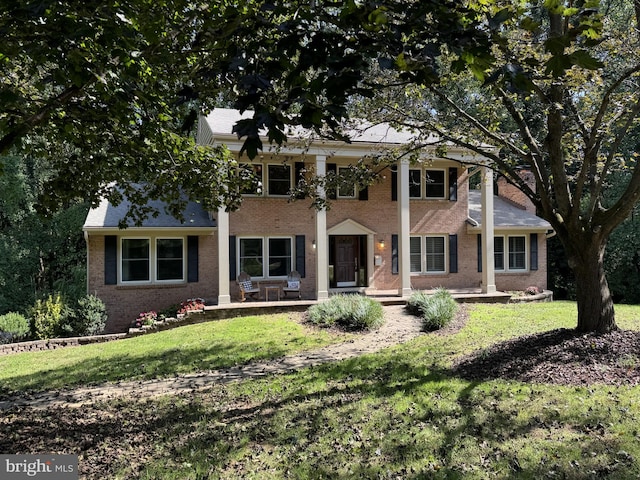 greek revival inspired property with brick siding and a front yard