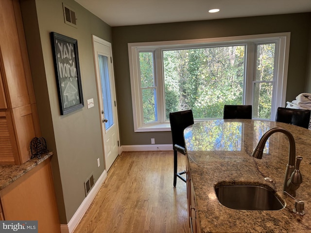 dining space with a healthy amount of sunlight, sink, and light wood-type flooring