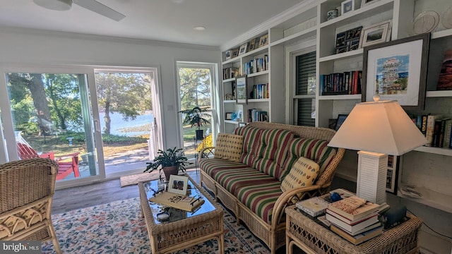 sitting room featuring built in shelves, hardwood / wood-style flooring, ceiling fan, and crown molding