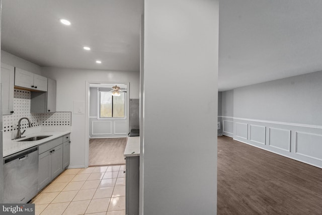 kitchen with sink, dishwasher, light wood-type flooring, and gray cabinetry