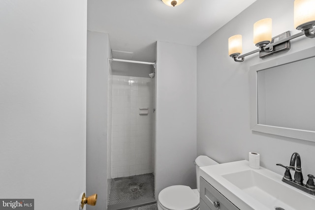 bathroom featuring a tile shower, toilet, and vanity