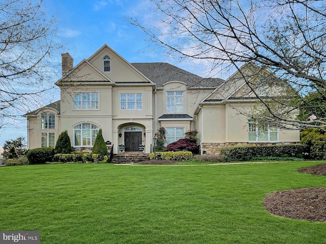 french provincial home featuring stone siding, stucco siding, a chimney, and a front lawn