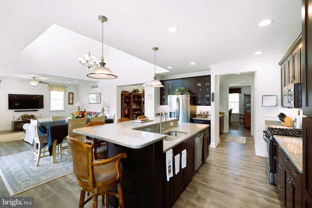 kitchen with dark brown cabinetry, sink, hardwood / wood-style floors, a kitchen island with sink, and appliances with stainless steel finishes