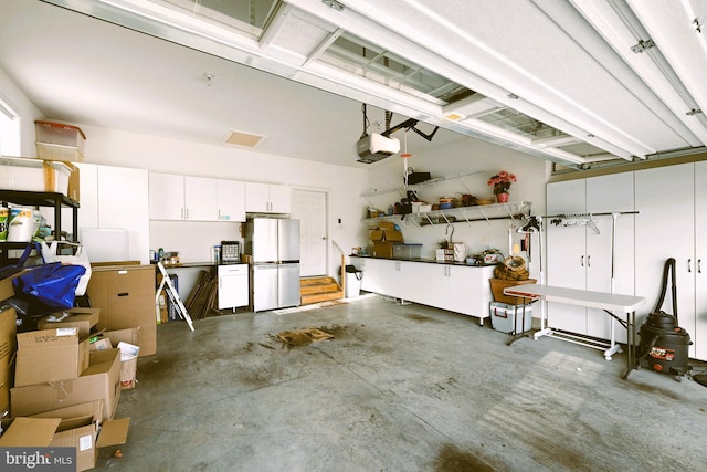 garage featuring stainless steel refrigerator and a garage door opener