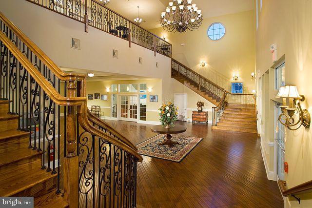 stairs with wood-type flooring, a high ceiling, and a chandelier