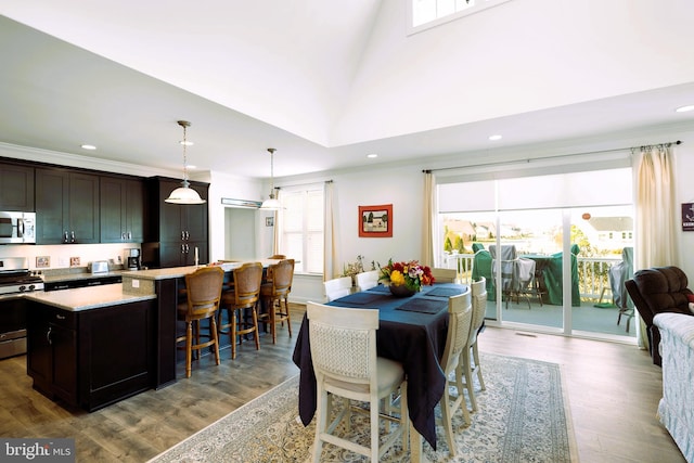 dining area featuring light hardwood / wood-style floors, high vaulted ceiling, and crown molding