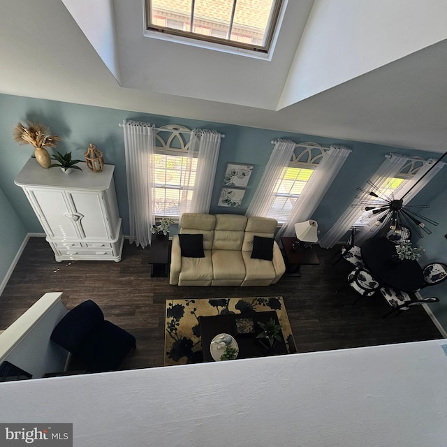 living room featuring dark wood-type flooring, a towering ceiling, and plenty of natural light